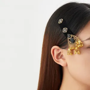 Gros plan de profil d’un modèle portant une barrette noire ornée de pierres et de clochettes dorées