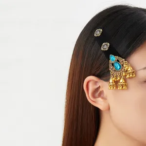 Vue de profil d’un modèle avec un ornement capillaire doré, pierres bleues et clochettes pendantes