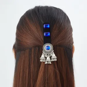 Rear view of half-up hair with a black clip, blue gems and dangling silver bell tassels