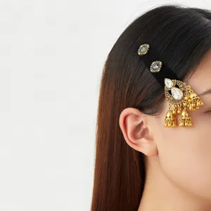 Accessoire noir pour cheveux, orné de strass et de pampilles dorées près de l’oreille