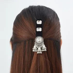 Back view of half-up hair with a black velvet clip, clear stones, silver filigree and bell tassels