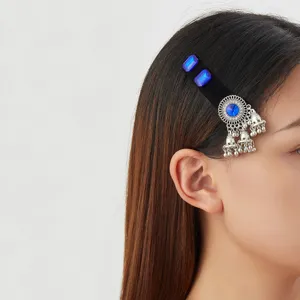 Black velvet hair clip with blue stones and silver bell tassels worn at the temple