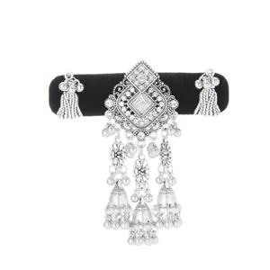 Ornate silver-tone ornament with clear stones, dangling bells and tassel-like chains on display