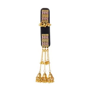 Detail view of gold filigree, pink rhinestones, and dangling bell tassels on a black velvet base
