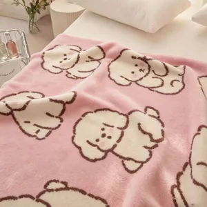 Couverture rose en flanelle avec de mignons chiens blancs et bruns, présentée sur un lit