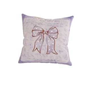 Square lavender plush cushion with a white polka-dot bow print on a white background