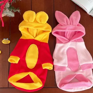 Flat lay of two plush pet hoodies: yellow-red with round ears and pink with long bunny ears