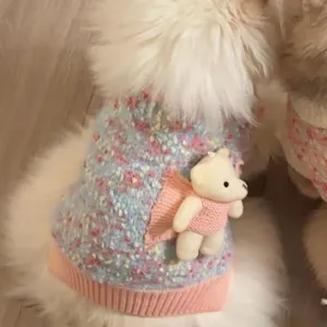 Primer plano de chaleco tejido azul jaspeado para mascota, con borde rosa y pequeño oso decorativo