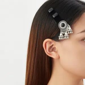 Side view of a model wearing a silver filigree hair clip with black stones and dangling bell tassels