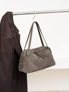 Taupe suede-textured handbag with leather handles and twin zippers, hanging beside a brown jacket