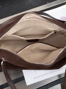 Close-up of the open bag interior, showing beige lining, a zip pocket and divided compartments