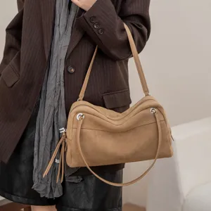 Tan suede-texture leather Boston shoulder bag with a soft pillow shape, carried by a model