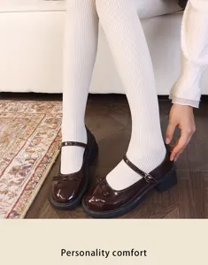 Close-up of white ribbed tights paired with glossy brown Mary Jane shoes and slim buckle straps