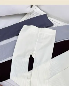 Flat lay of ribbed leggings in white, navy and gray tones, with the white pair centered
