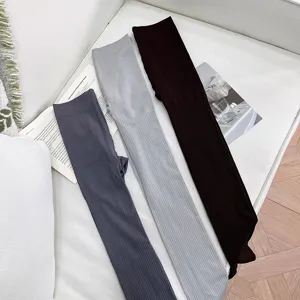 Three ribbed knit leggings in slate, light gray, and dark brown laid out on a white sofa.