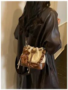 Model wearing a cream and brown quilted bucket bag, braided handle and teddy bear charm