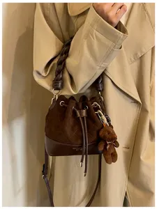 Brown suede-look bag worn crossbody, with leather base, braided handle, drawstring and teddy charm