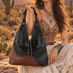 Sac cabas en cuir noir et brun, patchwork et pompon, porté dans un décor de désert