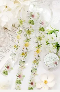 Floral decorative tape strips with pearl accents displayed beside a matching round storage tin