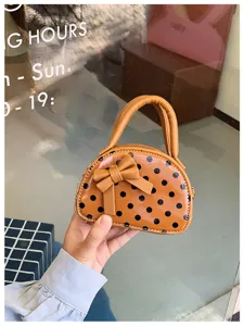 Close-up of a glossy brown polka-dot bag with a bow, double handles and a gold side chain