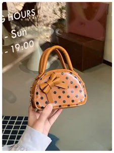 Close-up of a brown polka-dot mini bag with a bow, double handles and a metal chain strap