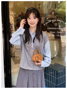 Girl holding a small brown faux-leather bag with a polka-dot bow and chain strap outdoors