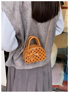 Back view showing a brown faux-leather mini bag with black dots, bow and gold chain strap