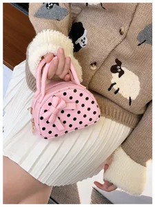 Close-up of a pink polka-dot mini bag with bow, rounded top, handles and gold-tone zipper