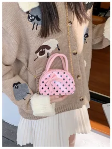 Lifestyle view of a pink polka-dot mini bag with bow and chain strap worn crossbody
