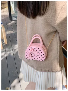 Back view of a person wearing a pink polka-dot mini bag with a bow and gold chain strap
