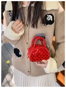 Red polka-dot bag with a bow and gold chain shown on a model against a beige knit outfit