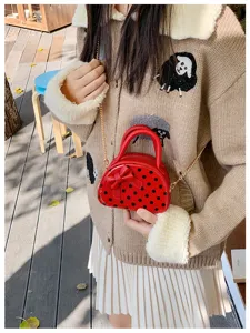 Red mini bag with black polka dots and a bow, worn with its gold chain strap across an outfit
