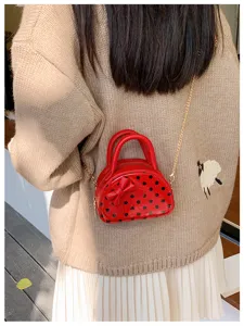 Back view of a person wearing a small red polka-dot bag with a bow, top handles and chain strap