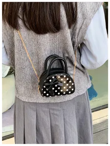 Back view showing a small black bag with white dots, a bow detail and a gold chain strap.
