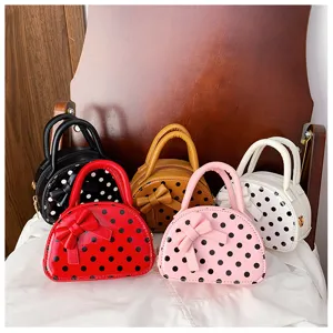 Five polka-dot bags with bow details in black, red, tan, pink and white, arranged side by side.