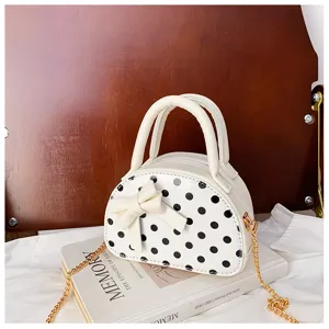 White dome-shaped bag with black polka dots, a front bow, top handles and gold chain strap