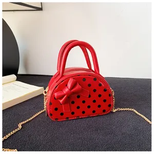 Red domed mini bag with black polka dots, a sculpted bow, twin handles and a gold chain strap