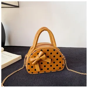 Mustard-yellow mini bag with black polka dots, a front bow and a gold-tone chain strap