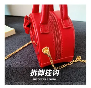 Close-up of the gold detachable metal hook and chain clasp beside the red bag's zipper