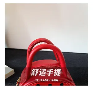Close-up of a red round mini bag with twin handles, perforated dots and a gold metal clasp