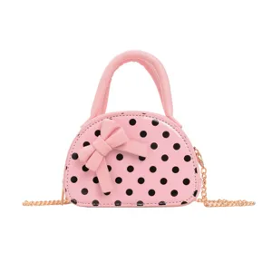 Close-up view of a pink polka-dot bag with a bow, top handle, and gold-tone chain strap.