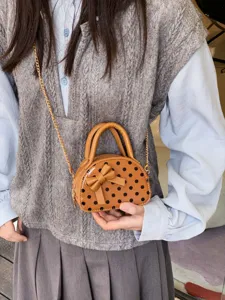 Girls' brown faux leather mini bag with black dots, bow detail and gold chain strap, worn crossbody