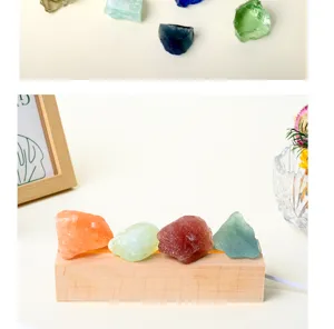 Cuatro cristales en bruto de colores sobre una base de madera clara, en una escena decorativa suave