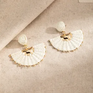 White woven half-moon earrings with gold-tone accents and tiny beads, displayed on linen