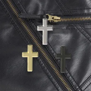 Close-up of three matte metal crosses in gold, silver, and black on a black leather jacket