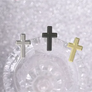 Three matte-finish metal crosses in silver, black, and gold arranged above a clear glass bowl.