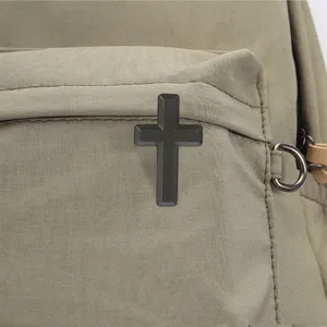 Close-up of a black raised cross-shaped badge on the textured front pocket of an olive backpack