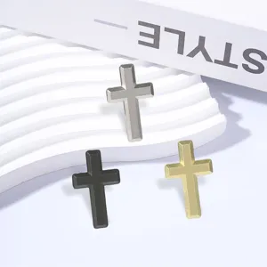 Three matte cross brooches in silver, black, and gold, arranged on a white display