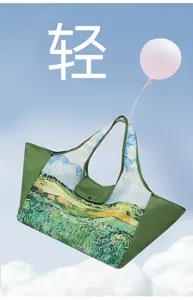 Green tote bag with a painterly field-and-sky print, shown against sky, clouds and a balloon