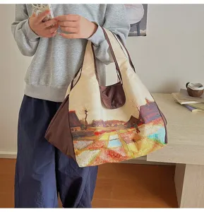 Lifestyle view of a person carrying a cream tote with a colorful landscape print and brown pouch